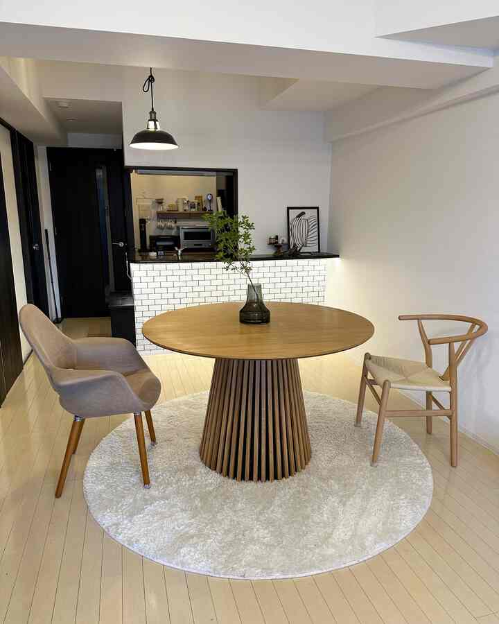 ナチュラルカラーとホワイトトーンのダイニング、丸い木製ダイニングテーブルと異なるデザインのダイニングチェアが配置されたシンプルな雰囲気の空間