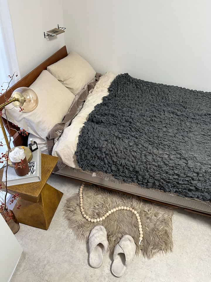 ベージュとグレーのトーンの寝室、モダンな木製ベッドフレームと快適な寝具が配置された雰囲気のあるインテリア