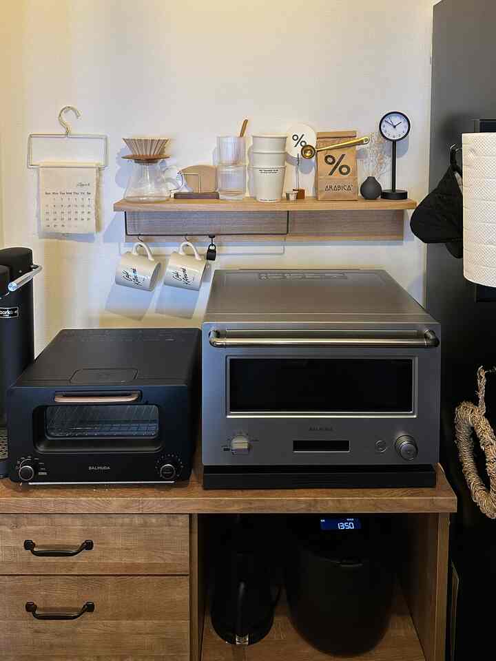 ナチュラルなブラウン色調のキッチン、壁に設置された棚にコーヒー器具とマグカップが配置されたシンプルで居心地の良いおうちカフェの空間