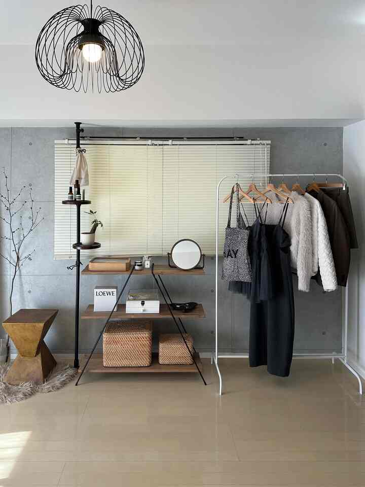 白とナチュラルカラーの小さなブティックスタイルの空間、洋服ラックとウッドシェルフ、ラタンバスケットが配置されたモダンなインテリア