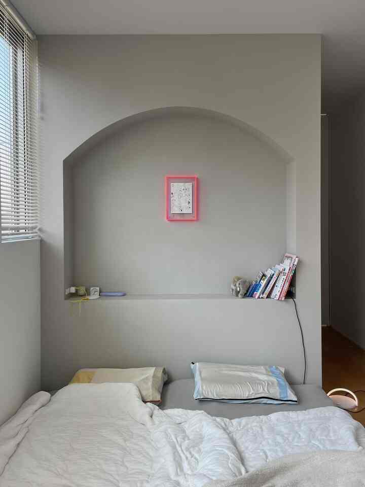 白とベージュの調和した寝室、印象的な大きなアーチ型のニッチとベッド、枕が置かれたシンプルなインテリア