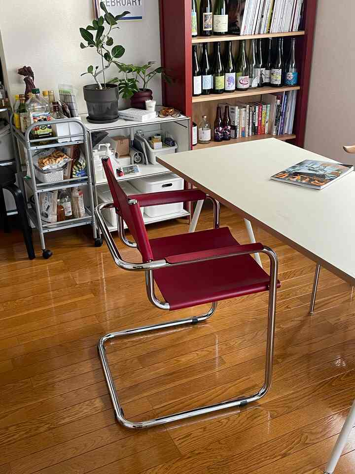 暖かいブラウンの木目調フローリングと落ち着いた赤色の椅子があるダイニング、飲み物と食品が整頓された実用的な空間