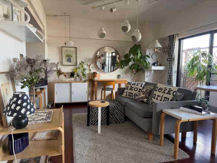 白と茶色のトーンの北欧風リビング、グレーのソファとペンダントライトが配置された雰囲気のある空間