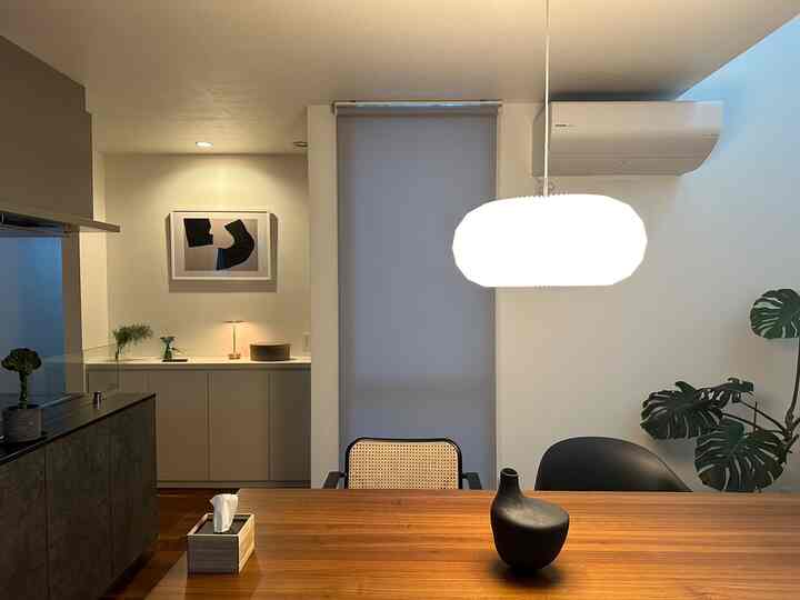 白い壁と茶色の木製ダイニングテーブルが配置された、モダンで北欧風のダイニング空間