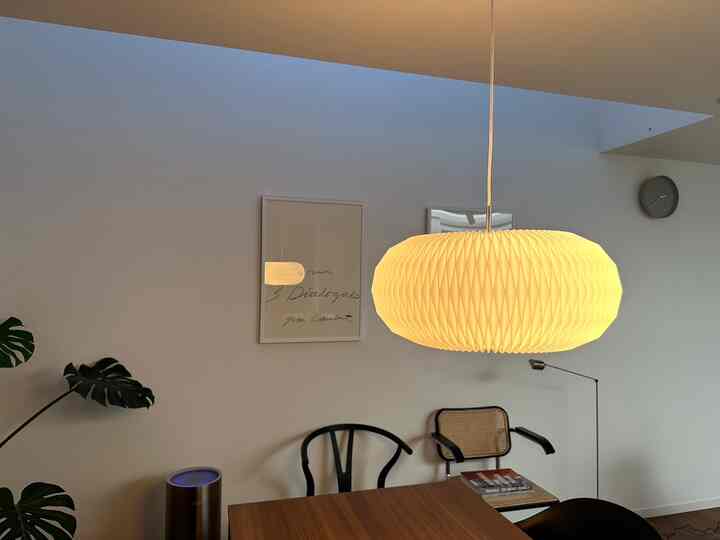 白い壁とブラウンのダイニングテーブル、シンプルなペンダントライトが配置されたナチュラルなダイニング空間