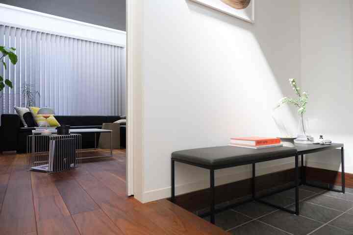 自然な色調の玄関、シンプルなベンチと木の床が配置されたモダンなインテリア