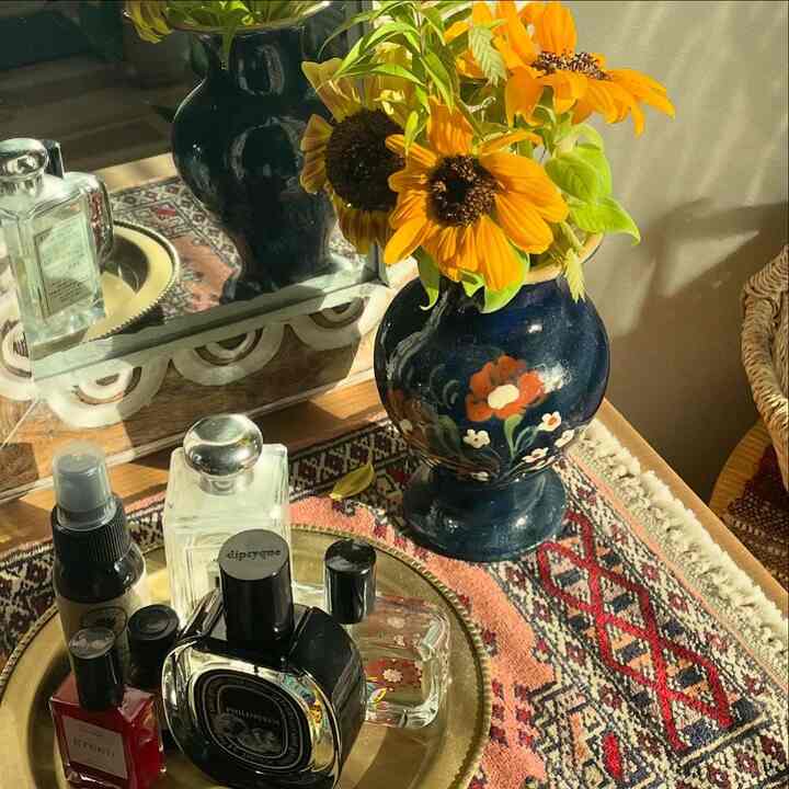 温かみのある黄色とネイビーのトーンが調和したボヘミアンスタイルの空間、民族模様のラグに花瓶と香水が配置された雰囲気のあるインテリア。