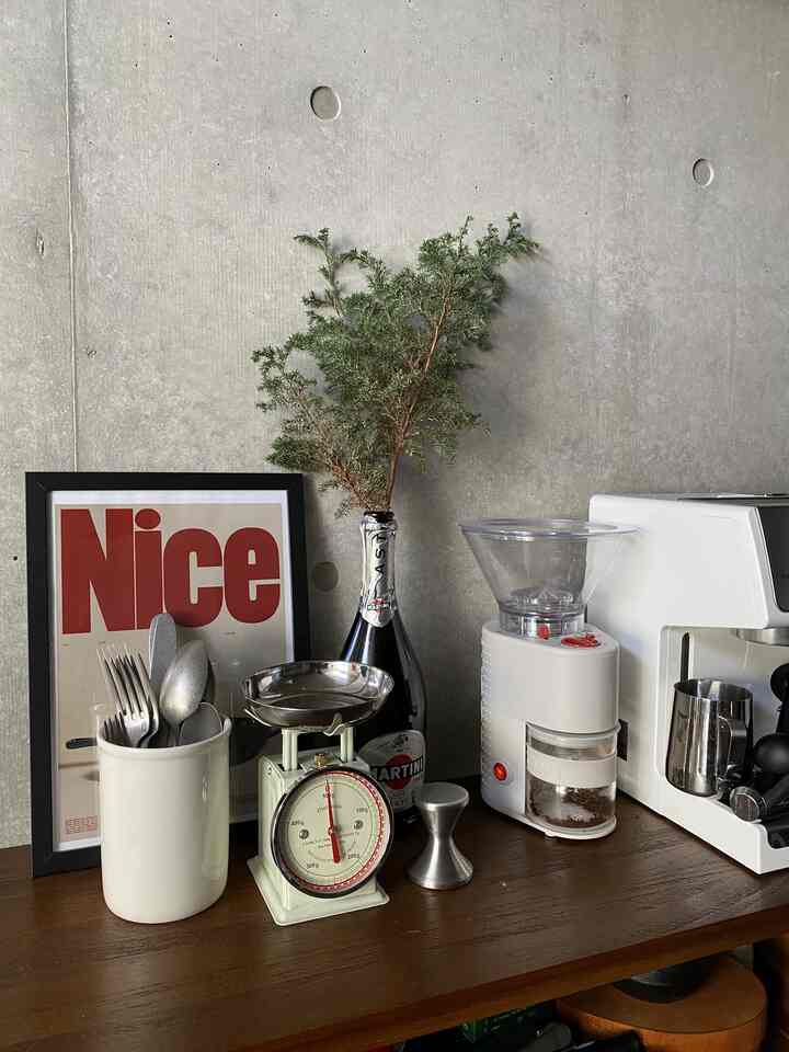 ホワイトのキッチン家電とブラウンの木目調テーブルの上にコーヒー器具と額縁が配置されたモダンで自然な雰囲気のキッチン