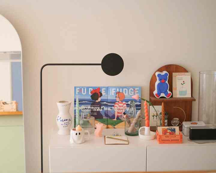 白とオレンジの色調が特徴のミニマルなリビング、きれいな棚の上にキャンドルと飾り物が配置されている