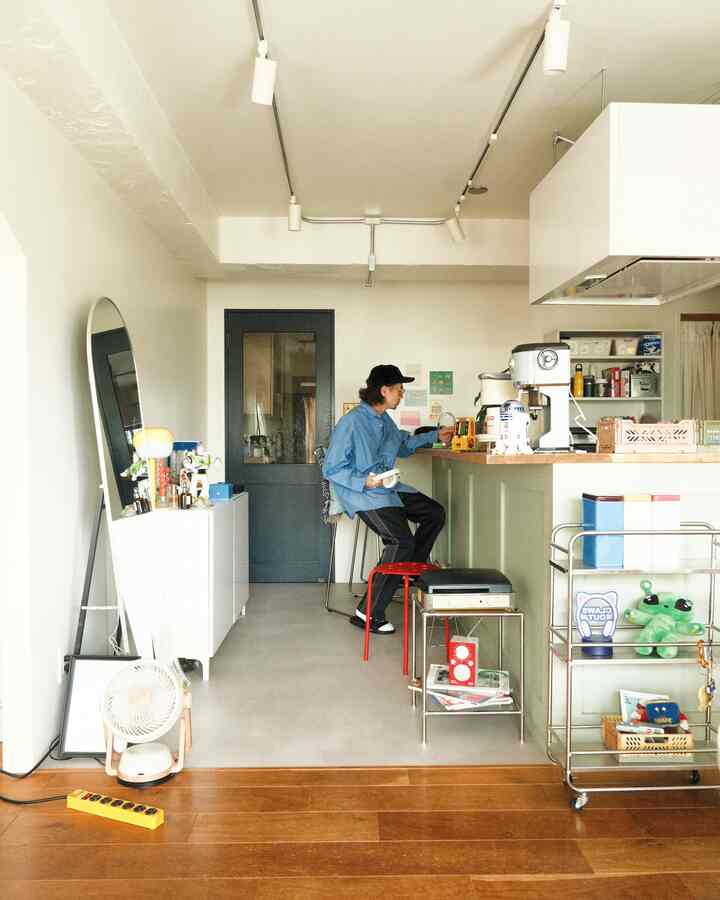 白と木目調でまとめられたコンパクトなキッチンスペース、キッチンカウンターとレトロ風スツールが置かれたシンプルなインテリア