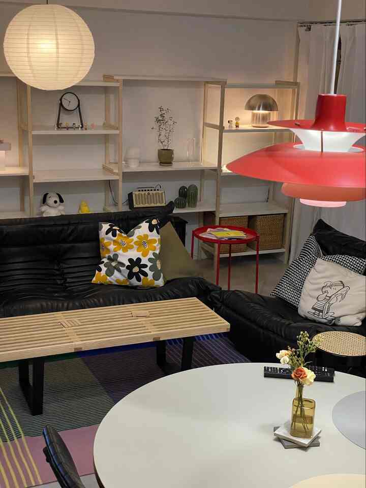 赤と黒の色調が特徴の北欧風リビング、黒のレザーソファと赤いサイドテーブル、丸いダイニングテーブルが配置された雰囲気のある空間