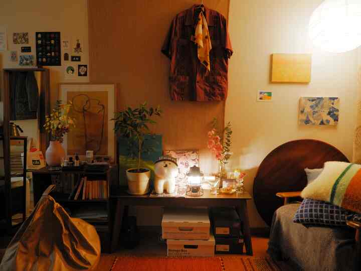 暖かいナチュラルカラーと木目調のリビング、ソファベッドと植物が配置された雰囲気のある空間