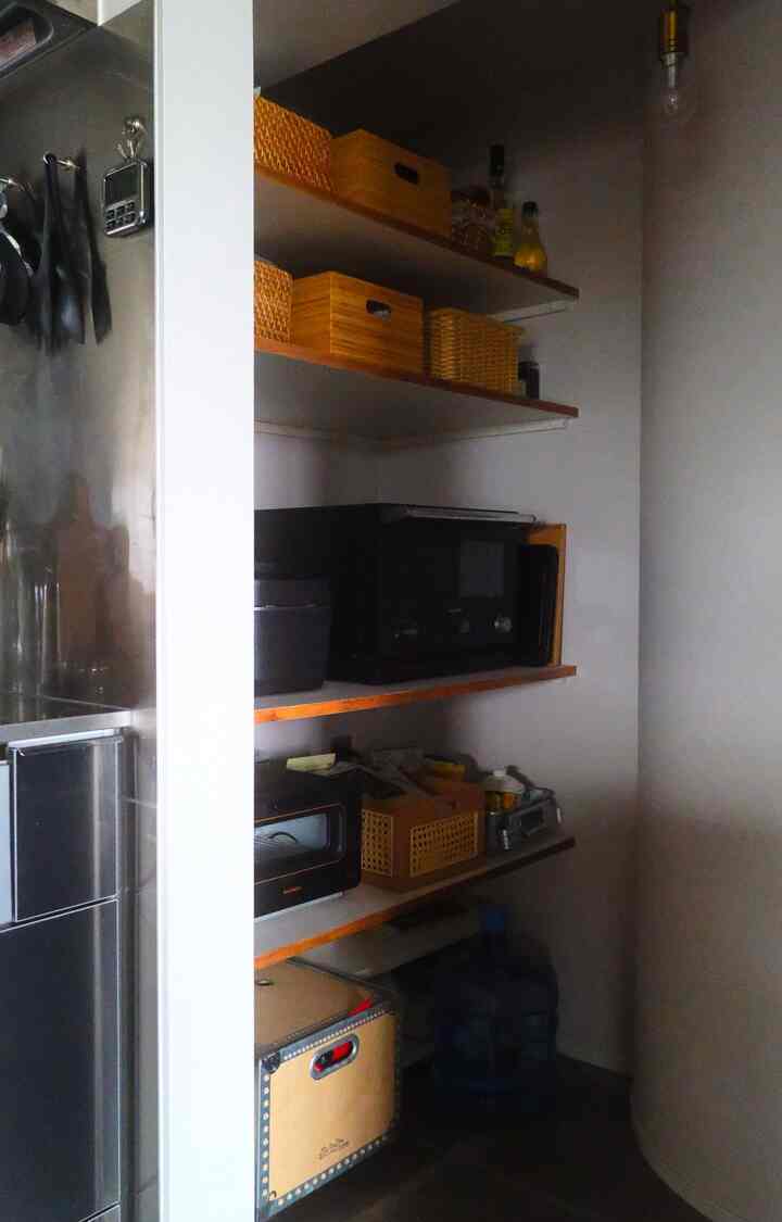 ブラウンの木製棚がある白い壁のキッチンパントリー、オーブンと収納ボックスが整然と配置された印象的な空間