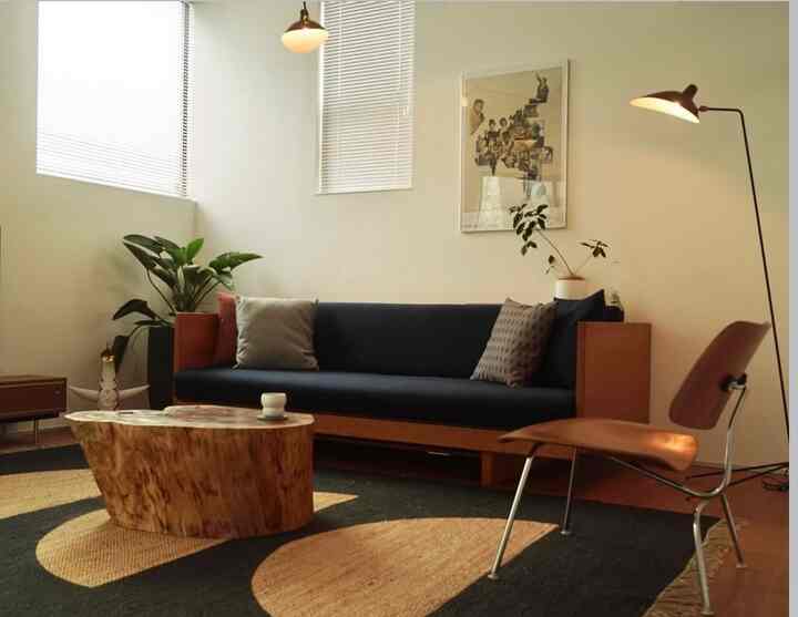 ネイビーソファとブラウンアームチェアが配置された自然素材を活かした照明のあるモダンなリビング