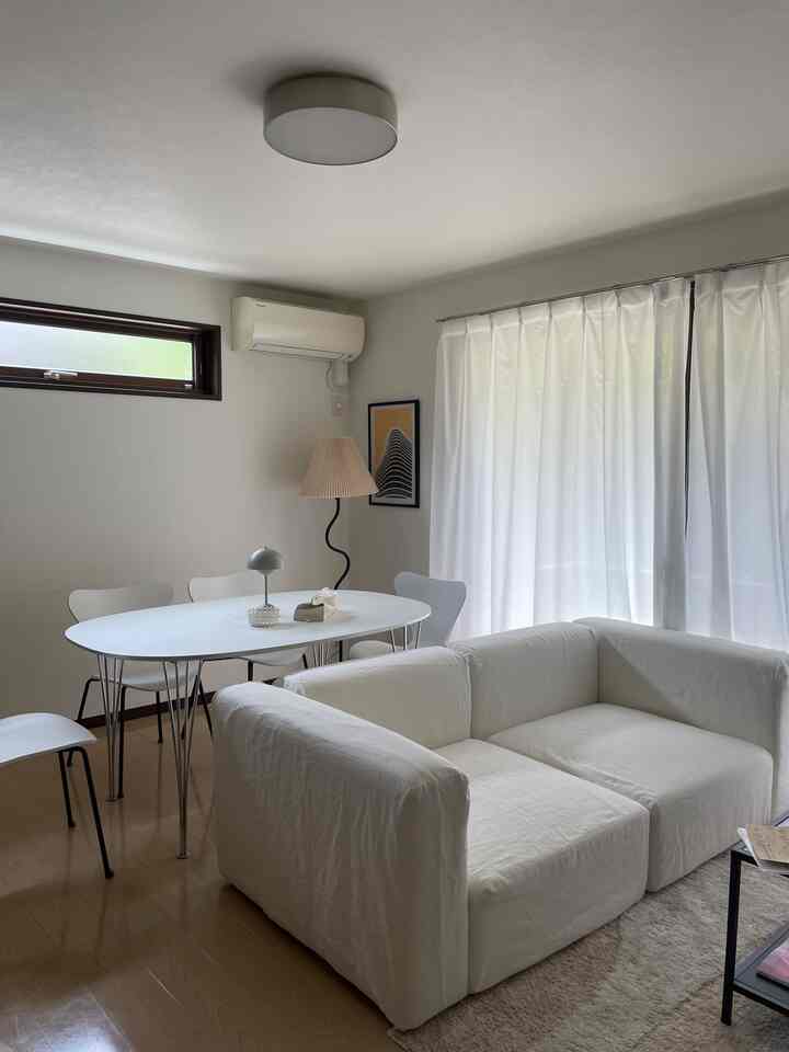 白を基調としたモノトーンのリビングとダイニングテーブルが配置された落ち着いた空間