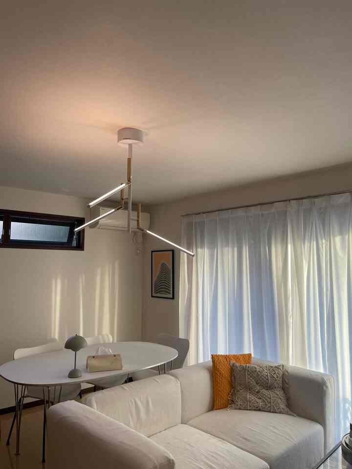 白を基調としたダイニングとリビングの空間、モダンなダイニングテーブルとソファ、黄色のクッションがアクセントの落ち着いた雰囲気