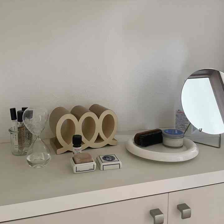 白とベージュのトーンの玄関収納棚、シンプルな小物と丸い鏡が配置された印象的な空間