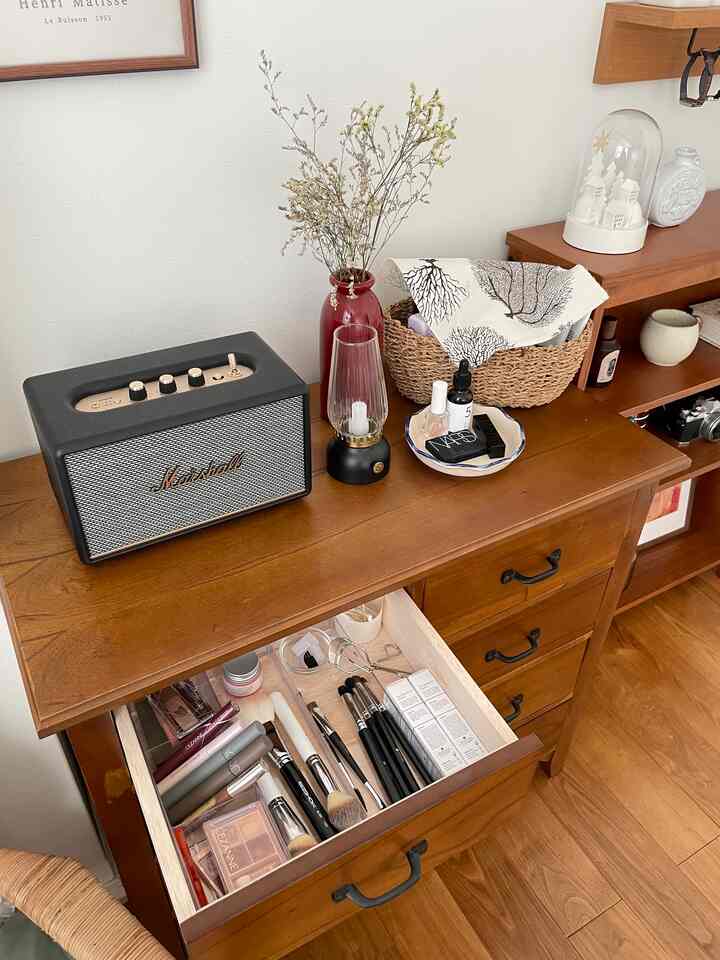 ナチュラルブラウン調のチェストにメイク用品とオーディオスピーカーが配置された雰囲気のあるインテリア