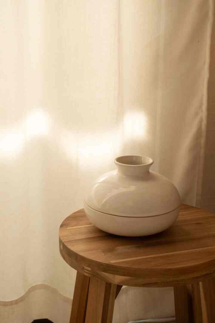 温かみのあるナチュラルトーンのキッチン、木製スツールの上にセラミック製の蚊取線香ポットが置かれたシンプルなインテリア