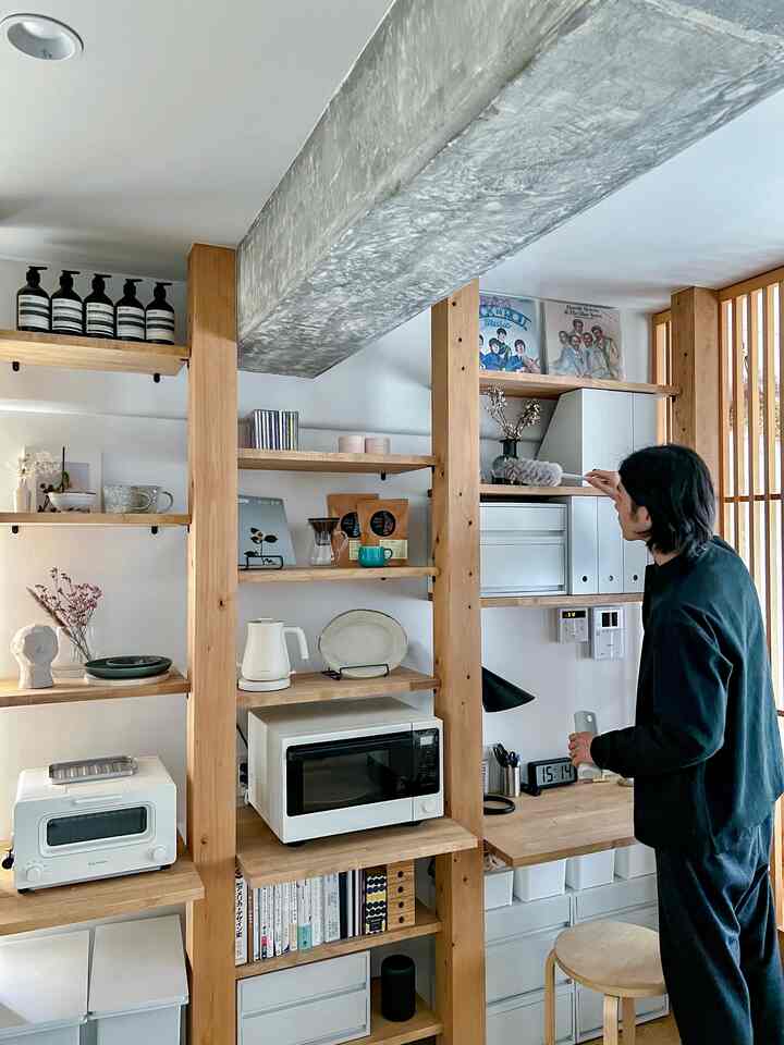 白とナチュラルトーンのキッチンスペース、バルミューダの電気ケトルとトースターが木製の棚に整然と配置されたインテリア