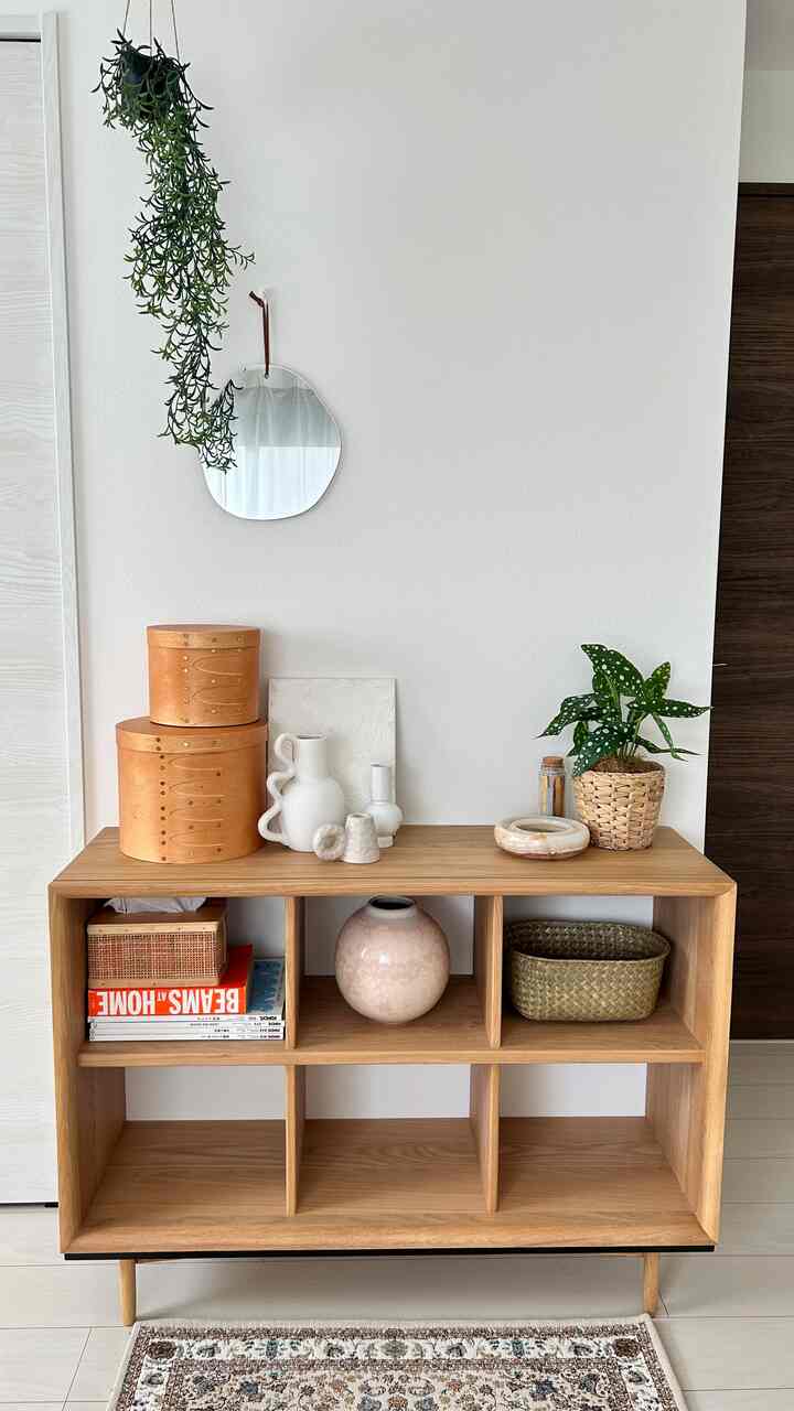 白い壁とナチュラルな木目調の棚、植物と収納小物が配置されたすっきりとした空間