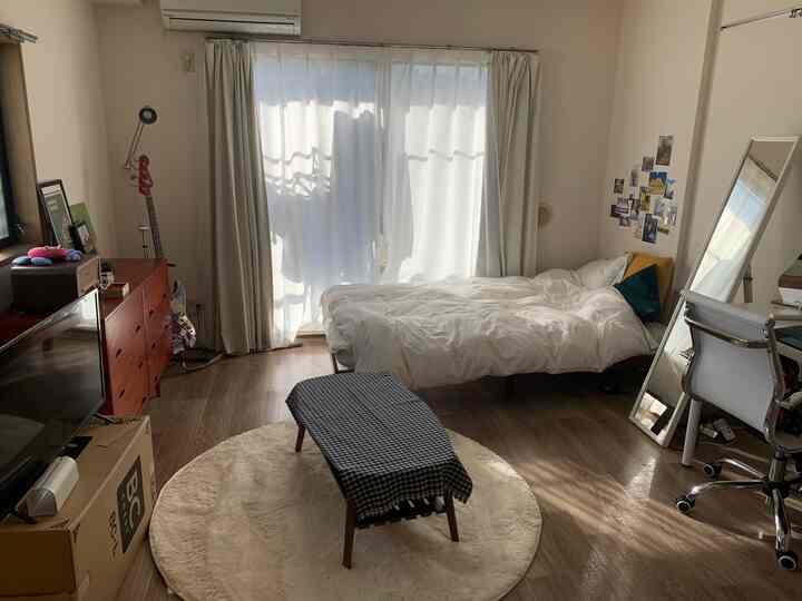 ベージュとブラウンのトーンの寝室、シンプルな家具と明るいカーテンが調和した一人暮らし向けの温かみのある空間