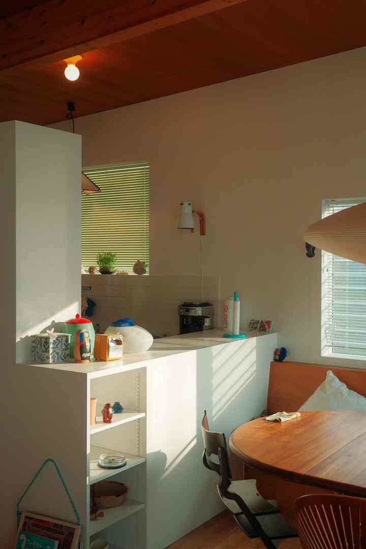 ナチュラルな木目調とホワイトカラーのキッチンとダイニング、木製のテーブルと椅子が配置された雰囲気のあるインテリア