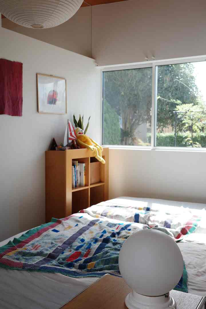 ナチュラルな色調の寝室、広い窓と木製収納が配置された温かみのある印象的な空間