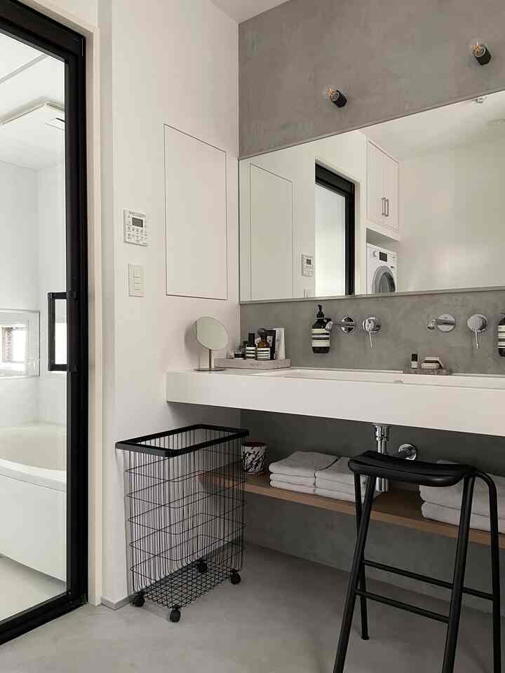 グレーとホワイトのトーンのバスルーム洗面台スペース、整然とした収納とホテルライクなモダンインテリア