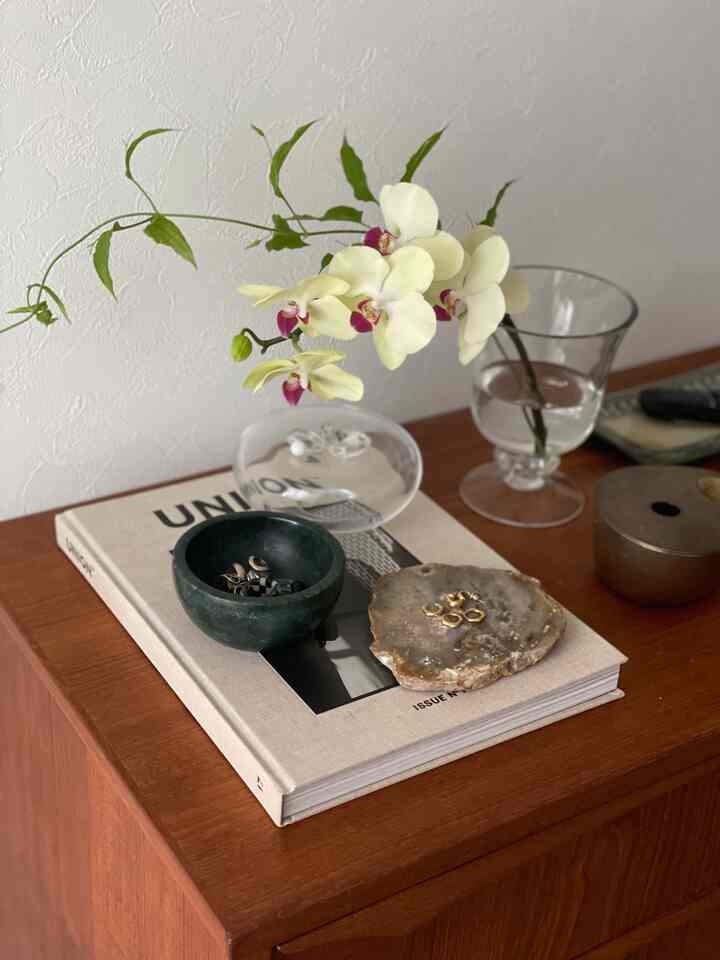 ナチュラルな木目調のチェストの上に蘭の花とアクセサリーが整えられた印象的なディスプレイスペース