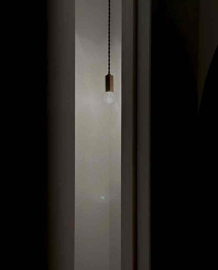 白を基調としたトイレスペースに、ゴールドの真鍮ペンダントライトが配置されたモダンで雰囲気あるインテリア