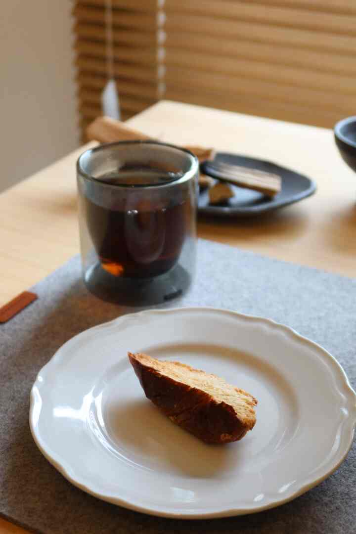 グレーの机の上に白い皿と黒いコーヒーカップが置かれたミニマルなホームカフェ空間