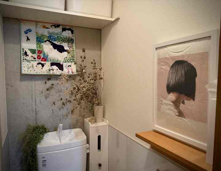 白とナチュラルカラーのトイレ、シンプルな装飾と額縁が配置された雰囲気のあるインテリア