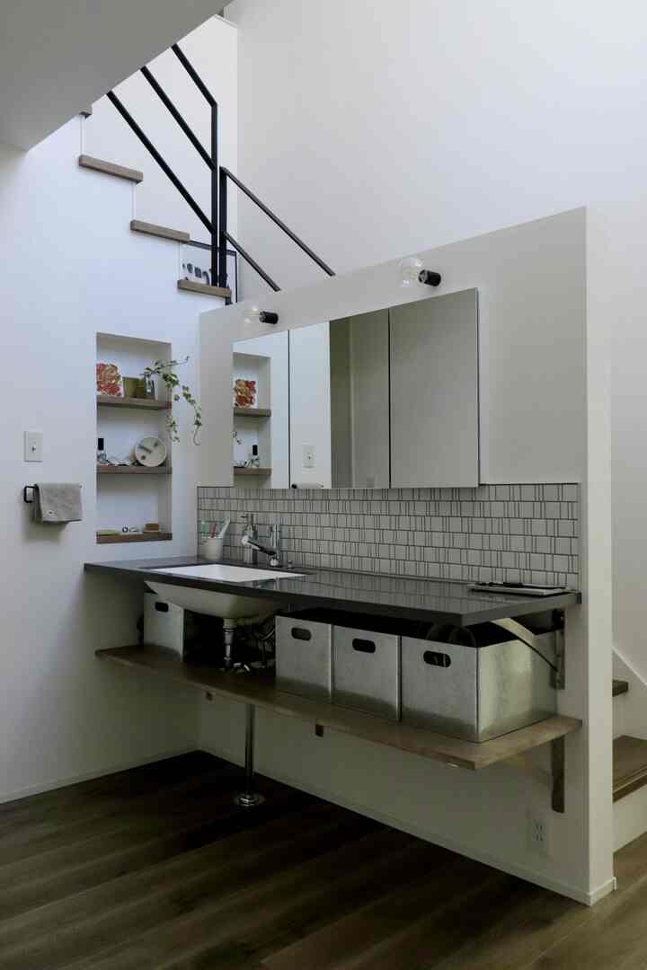 白とグレーのトーンが調和した狭いバスルーム空間、モダンな収納ボックスと大きな鏡が配置された印象的な玄関型洗面所