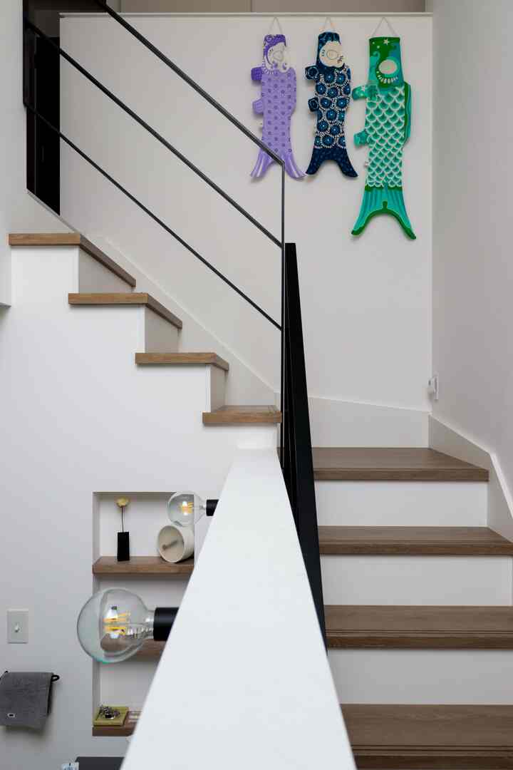 白とナチュラルカラーの階段空間、壁にカラフルなこいのぼりが飾られた雰囲気のあるインテリア