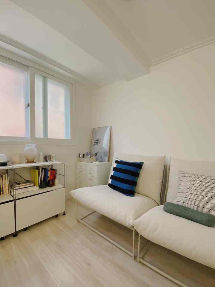 White and wood-toned compact workroom featuring a clean sofa and bookshelf in a minimal natural style