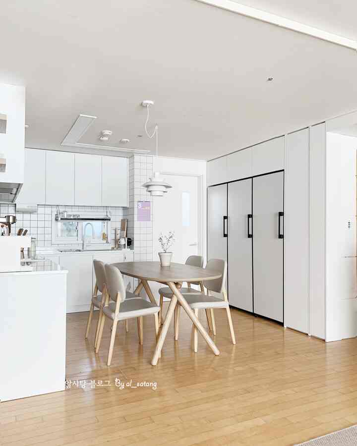 Bright white toned kitchen and dining space featuring a natural wood table and chairs with a modern aesthetic