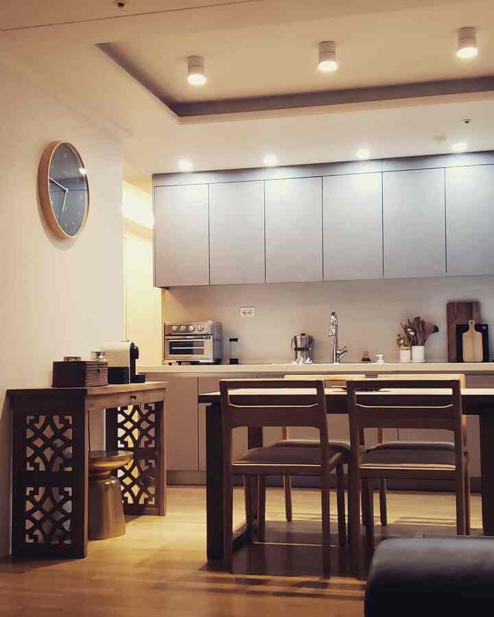 Modern dining space featuring wood tones and white kitchen with dining chairs arranged centrally