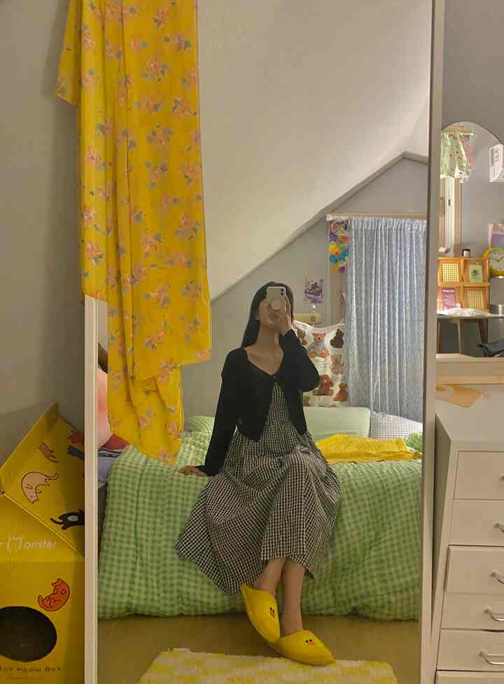 Yellow and green toned studio bedroom featuring a chest of drawers and curtains in a cozy layout