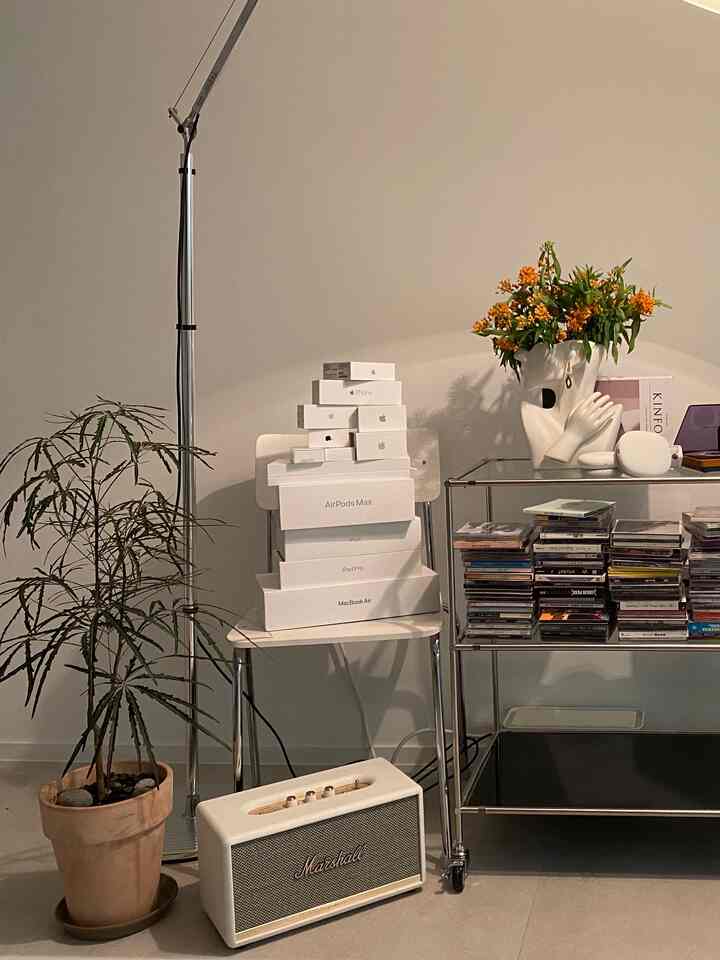 白とベージュのトーンのホームオフィス、アップル製品の箱とマーシャルスピーカーが配置されたモダンなインダストリアルスタイルのインテリア