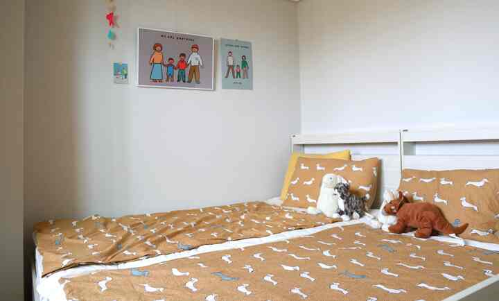 白い壁とベッドフレーム、ブラウンの掛け布団と子供用ぬいぐるみが配置された二人用の子供部屋