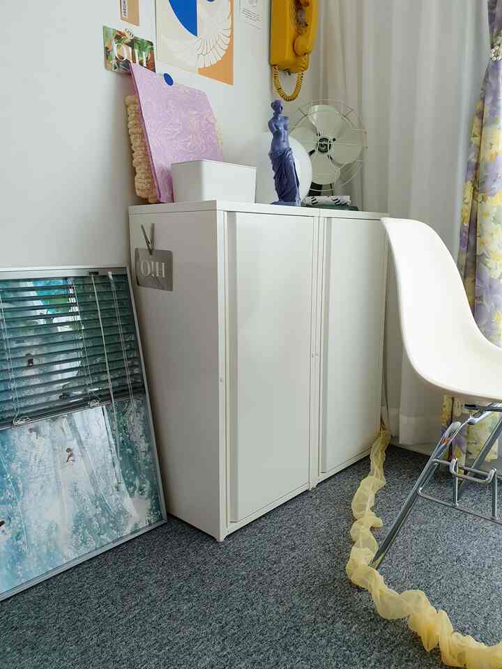 A white-toned small room featuring a cabinet and dining chair with a clean and practical atmosphere