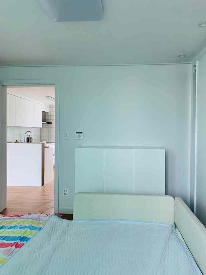 Clean modern bedroom with white and wood tones, featuring a built-in closet and a family bed