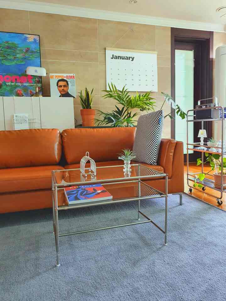 Warm brown and natural green plants harmonize in a modern living room with an orange leather sofa and glass coffee table