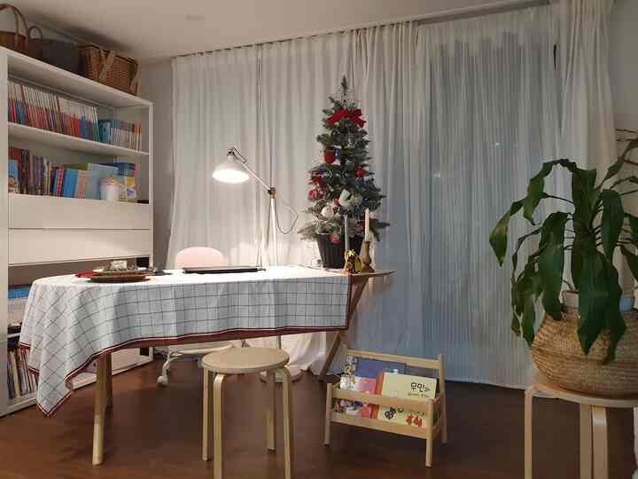 White and wood-toned home office living room featuring a round table and bookshelf in a cozy Christmas-themed setting