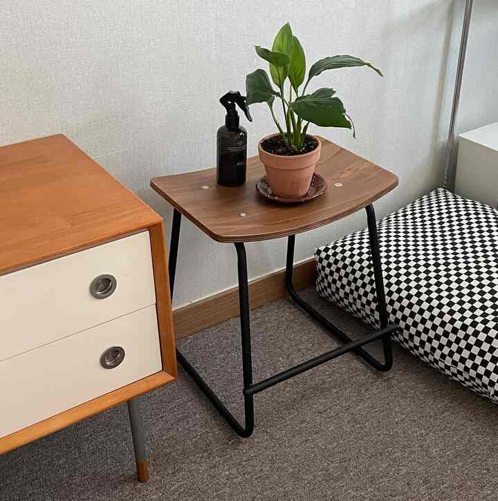 Wood tone and black-framed stool with wooden dresser arranged in a compact studio apartment interior