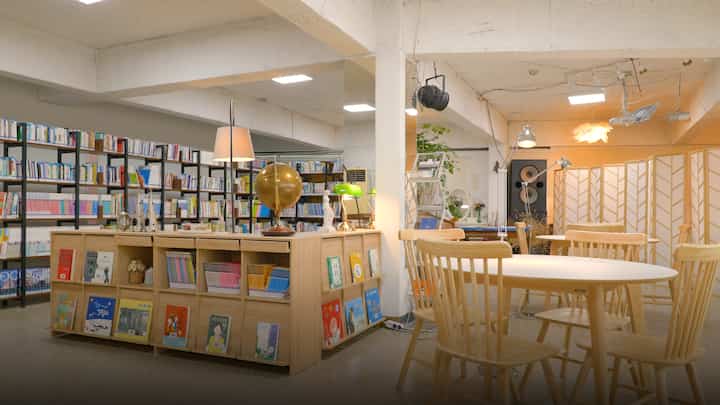 Natural-toned study room featuring wooden desks and bookshelves in a cozy reading area