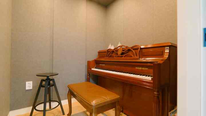 Natural-toned small piano room featuring a wooden piano and leather bench, creating a serene space