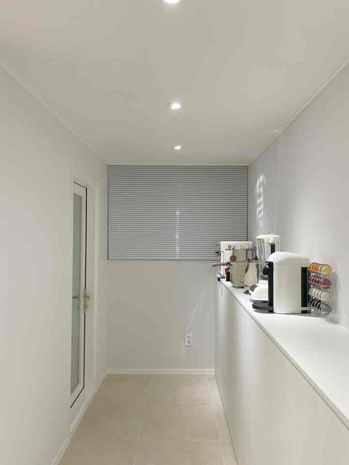 Beige-toned tiled floor and white walls with a long white cabinet, arranged as a secondary kitchen interior space