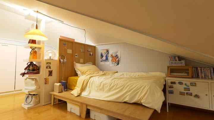 White and wood-toned loft featuring a cozy yellow bed, posters, and clever storage solutions